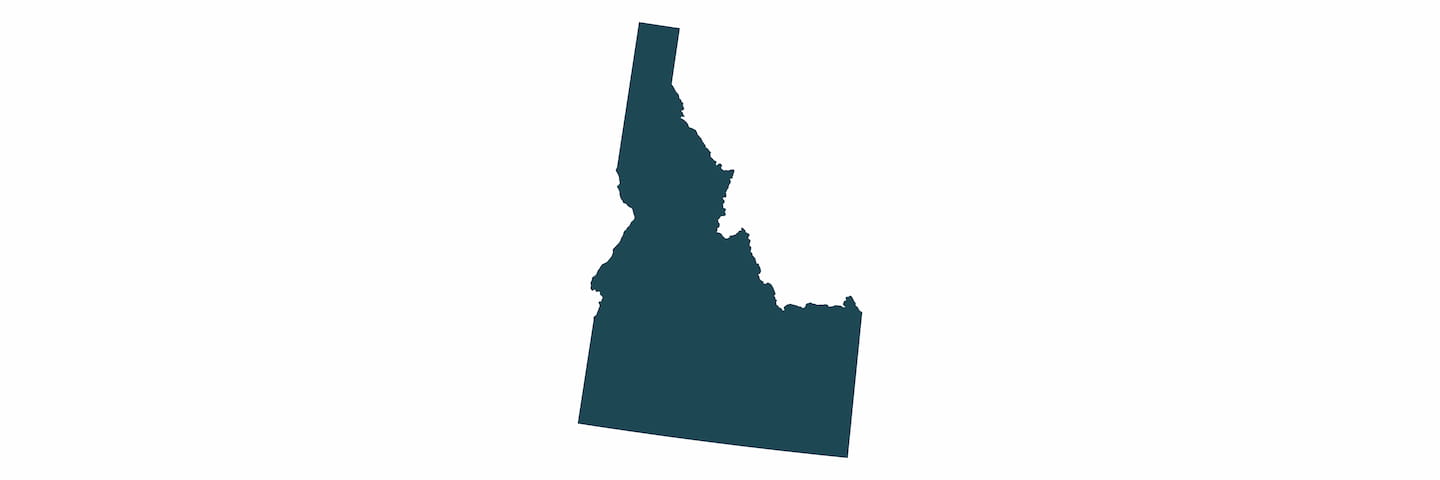 A simple, flat silhouette of the state of Idaho in dark blue color on a white background.